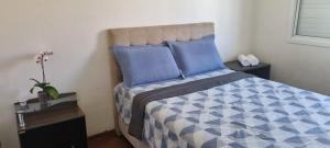 Schlafzimmer mit einem Bett mit einer blauen und weißen Bettdecke in der Unterkunft Casa no Moradas in Pelotas