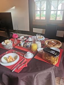 uma mesa com comida para o pequeno-almoço numa toalha de mesa roxa em Le Petit Verger em Grumesnil