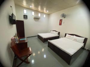 um quarto com duas camas, uma mesa e uma cadeira em Hotel Cát Tường em La Gi