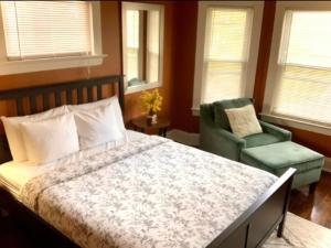 een slaapkamer met een bed, een stoel en ramen bij The House Hotels - Ridgewood Upper in Lakewood