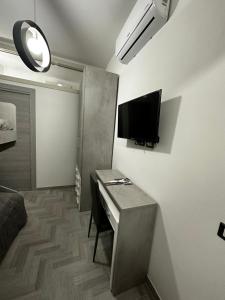 Kleines Zimmer mit einem Schreibtisch und einem TV an der Wand. in der Unterkunft Alloggio Pulcinella 2 Affittacamere in Acerra