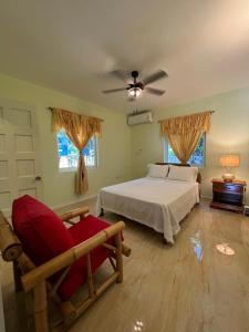 a bedroom with a bed and a chair and windows at Stoney Gate Cottages in Negril