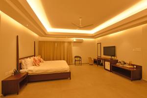 a bedroom with a bed and a flat screen tv at Manohari The Tea Retreat in Dibrugarh