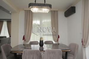 ein Esszimmer mit einem Tisch, Stühlen und einem Kronleuchter in der Unterkunft Vila Mikeli in Podgorica