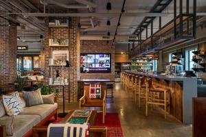 a restaurant with a bar and a couch and chairs at Moxy Charleston Downtown in Charleston