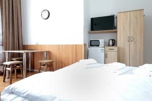 a hotel room with a white bed and a kitchen at Deluxe Apartments on Doroshenka 29 in Lviv