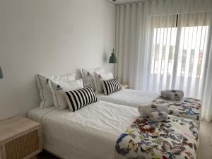 - 2 lits dans une chambre dotée de murs blancs et d'une fenêtre dans l'établissement Casa da Zéfinha - Villa, em Cinfães, no Douro, à Cinfães