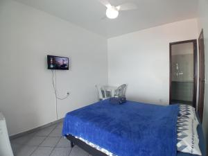 1 dormitorio con 1 cama azul y TV en la pared en Vista Mar Suítes, en Cabo Frío