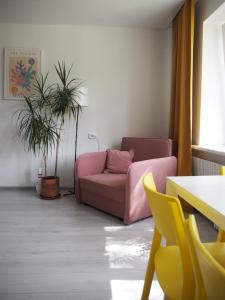 una sala de estar con un sofá rosa y plantas en Sunny apartment with lake and forest view, en Visaginas