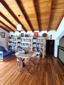 a living room with a table and shelves of books at Morada do Ipê Pousada in Chapada dos Guimarães