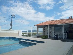 una casa con piscina frente a una casa en Vista Mar Suítes, en Cabo Frío