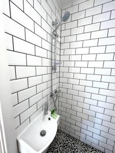 un bagno piastrellato bianco con lavandino e doccia di Flat 12, 10 St John’s Road a Bournemouth