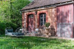 ein altes Backsteinhaus mit zwei Stühlen im Hof in der Unterkunft Maison Corbionne - Au cœur du Perche in Condeau