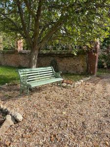 a green park bench sitting under a tree at Maison Corbionne - Au cœur du Perche in Condeau