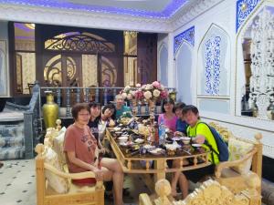 um grupo de pessoas sentadas à volta de uma mesa numa sala em Hotel Rizqiro'z Boutique em Bukhara