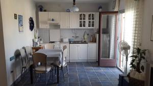 - une cuisine avec des placards blancs, une table et des chaises dans l'établissement Apartment Nera, à Sali