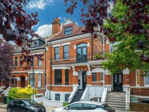 a brick house with two cars parked in front of it at Hidden Gem with En-Suites in West Hampstead in London