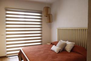 a bedroom with a bed with two pillows and a window at Residencias La Estación San Miguel de Allende in San Miguel de Allende