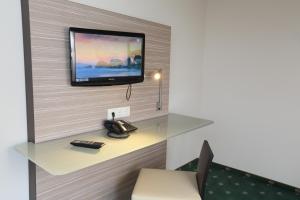 a room with a tv on a wall with a telephone at Jeddinger Hof Land- und Seminarhotel in Visselhövede