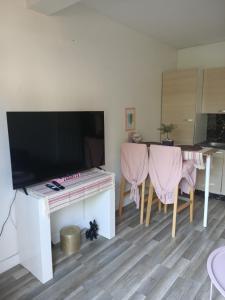- un salon avec une télévision et une table avec des chaises dans l'établissement La rose des sable, à Garges-lès-Gonesse
