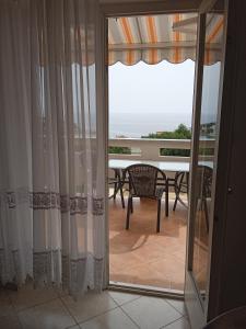 a glass door leading to a balcony with a table and chairs at Apartmani Vesna in Lun