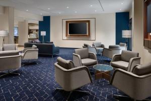 a waiting room with chairs and a flat screen tv at Courtyard by Marriott New Orleans Metairie in Metairie