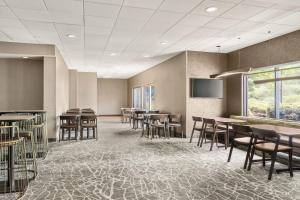 a waiting room with tables and chairs and a flat screen tv at SpringHill Suites Boston Andover in Andover