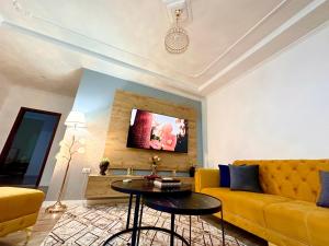 - un salon avec un canapé jaune et une table dans l'établissement The Luxe Apartments, à Gjirokastër