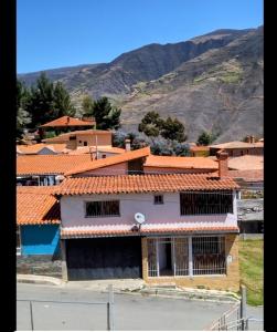 a building with orange tiled roofs with mountains in the background at Hospedaje Mérida in San Rafael