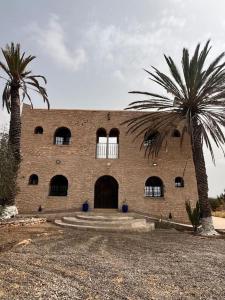 un bâtiment en briques avec deux palmiers devant lui dans l'établissement Villa Essaouira, à Essaouira