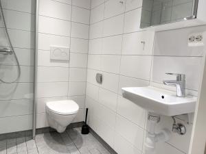 a white bathroom with a toilet and a sink at The Hedge Apartments in Oslo