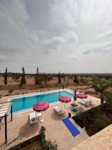 - une vue sur la piscine bordée de parasols et de chaises dans l'établissement Villa Essaouira, à Essaouira