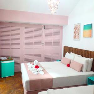 a bedroom with a large white bed with pink walls at Pousada Meraki Beach in Maragogi