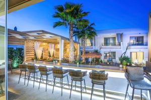 a patio with chairs and a bar with palm trees at Pefki Deluxe Residences in Pefkochori