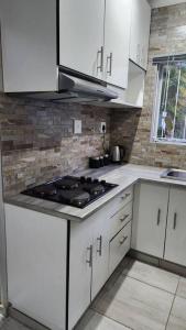 a kitchen with white cabinets and a stove top oven at Tranquility on St James in Johannesburg