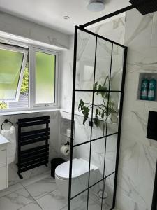 een witte badkamer met een toilet en een raam bij Large NEW Detached House Woolton, Families, FREE Parking, Massage, BBQ, Play room & MORE in Woolton