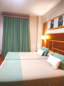 duas camas num quarto de hotel com cortinas verdes em Hotel Carmen em La Carlota