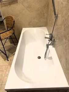 una vasca bianca in bagno con sedia di Villa La Passione Charme House a Venarotta