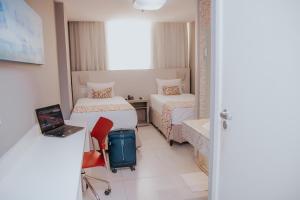 a room with two beds and a laptop and a chair at Rede Andrade Lapa in Rio de Janeiro +46 photos