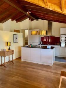a large kitchen with white cabinets and a table at Maison à louer in Saint-Prex