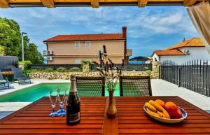 a table with a bowl of fruit and two bottles of wine at Vintage Residence Dramalj, pool self-use in Dramalj