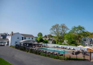 a pool with tables and chairs next to a house at Cape Colony Inn in Provincetown