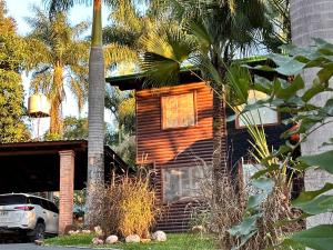 a wooden house with a palm tree in front of it at Costa del Sol Iguazú in Puerto Iguazú