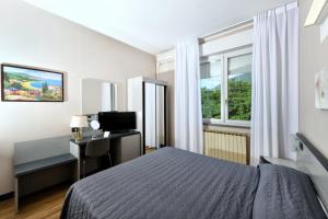 Schlafzimmer mit einem Bett, einem Schreibtisch und einem Fenster in der Unterkunft Hotel Internazionale in Domodossola