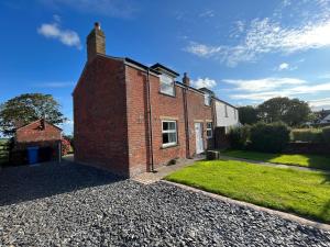 une maison en briques sur une allée de gravier dans l'établissement Newton Hall Farm cottage, hot tub garden views Nr Lytham Ribby, à Preston