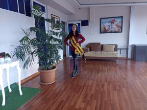 a woman standing in a living room with a plant at Hotel Versailles in Ambato