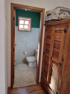 a bathroom with a toilet and a wooden door at Pousada Reserva Nativida in Santo Antônio do Pinhal