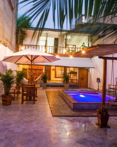 an outdoor patio with a swimming pool and umbrella at HOSTAL LA BOQUILLA in Cartagena de Indias