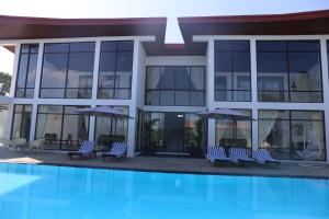 a building with chairs and umbrellas next to a pool at Amanda Beach Resort in Pasikuda