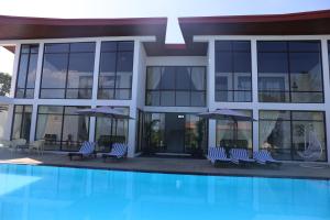 um edifício com cadeiras e guarda-sóis ao lado de uma piscina em Amanda Beach Resort em Pasikuda